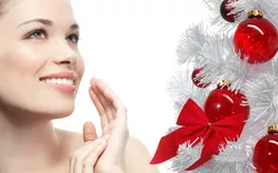 A woman is posing in front of a christmas tree.