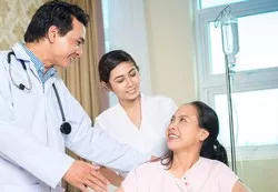 A doctor engages with a patient in a hospital bed amid the Smith Plastic Surgery's new Medical Concierge Program.