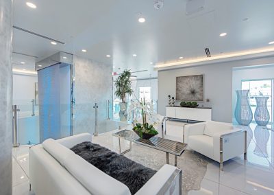 A living room with white furniture and a glass table.