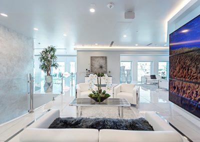 A white living room with a large painting on the wall.