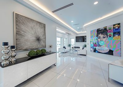 A white living room with a large painting on the wall.
