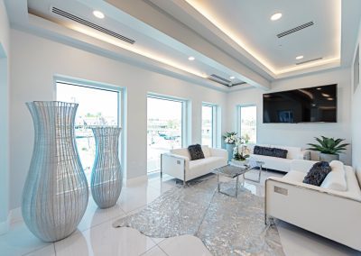 A living room with white furniture and a tv.