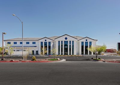 A building with a white exterior and a parking lot.