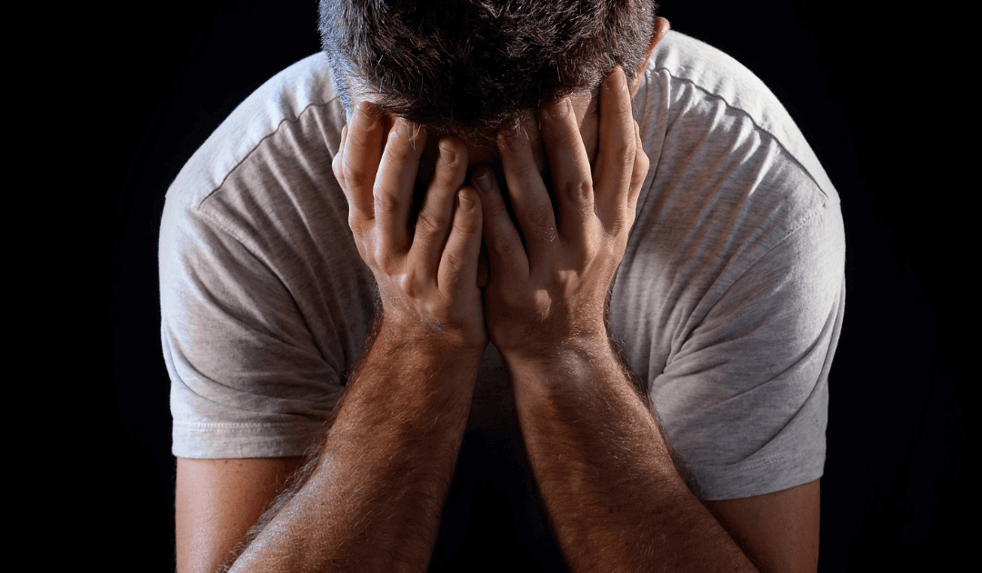 Distressed man covering his face, symbolizing emotional impact of male gynecomastia.